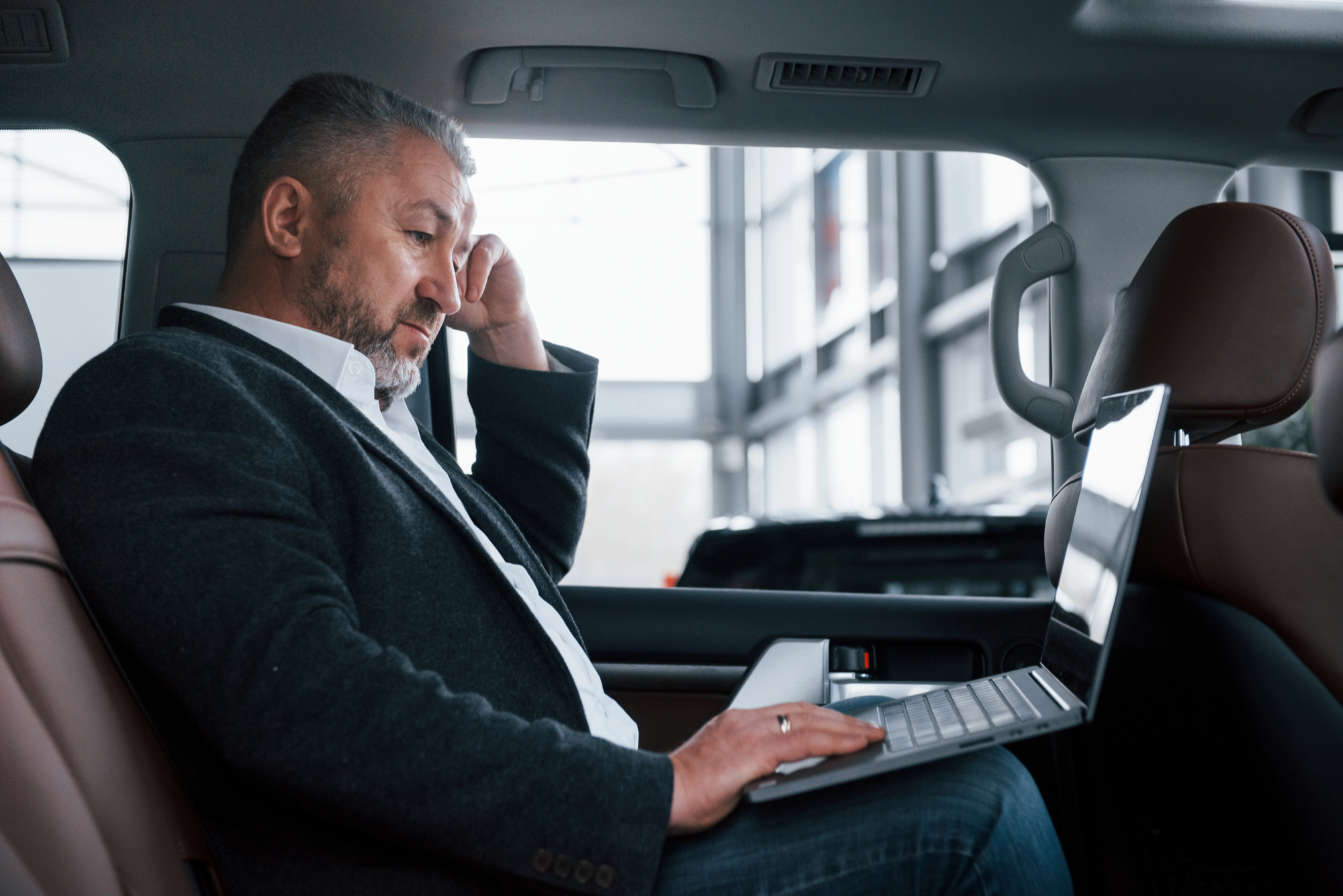 side-view-working-back-car-using-silver-colored-laptop-senior-businessman
